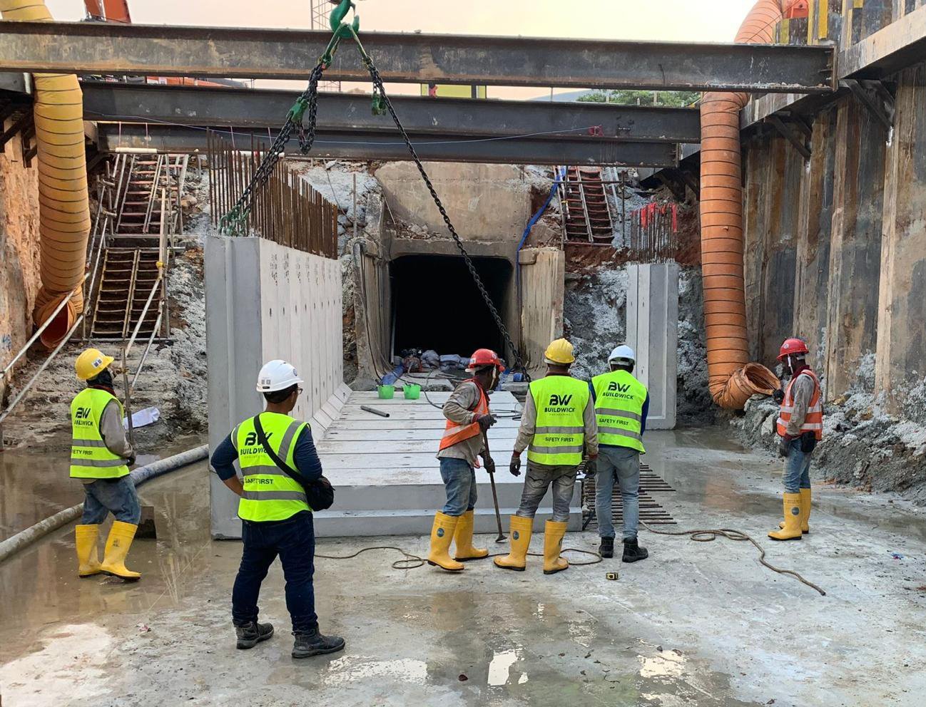 Buildwick crew lowering precast drainage panel into excavated trench