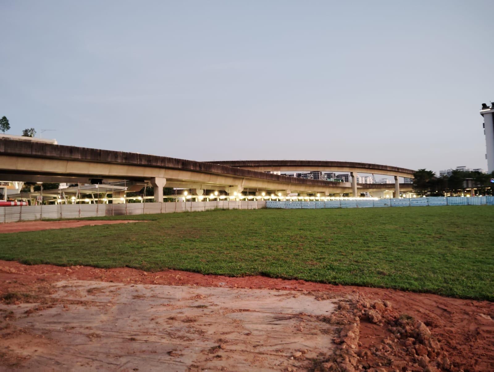 Turfing and site reinstatement under an MRT viaduct at dusk