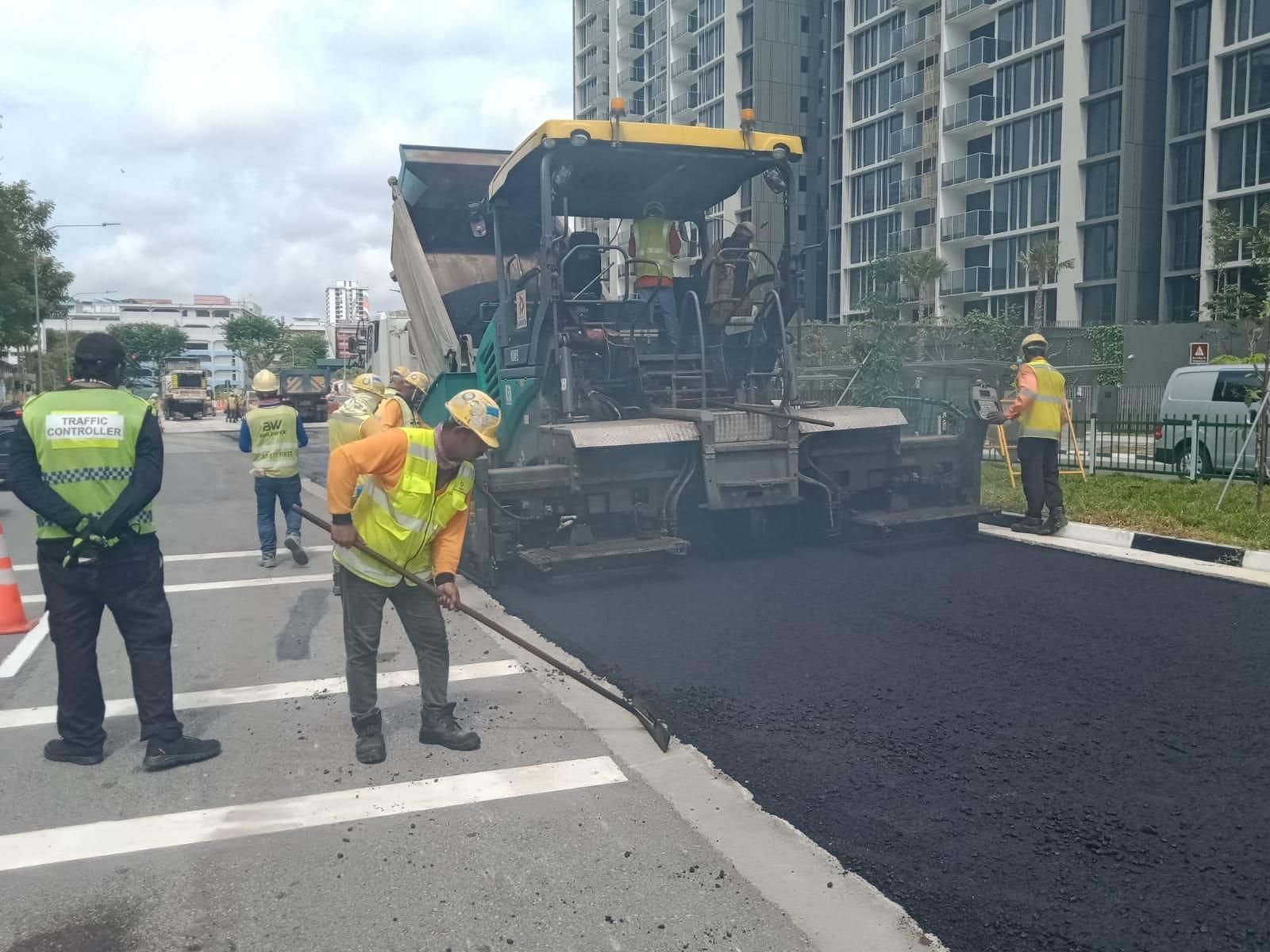 Asphalt paver machine and workers laying new road surface